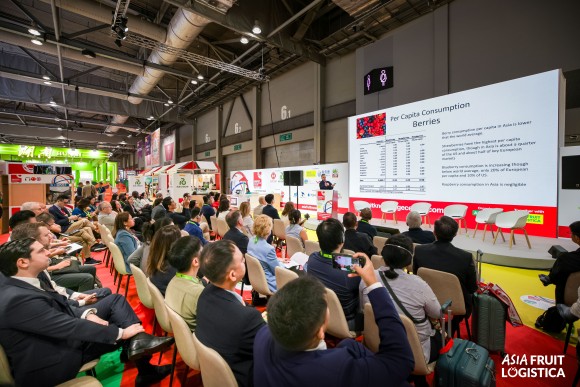 Many people sitting on chairs looking at a stage.