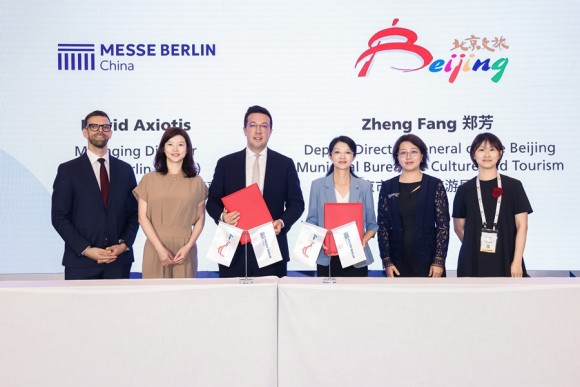 Six persons in front of a backdrop, two persons holding the MoU in their hands.