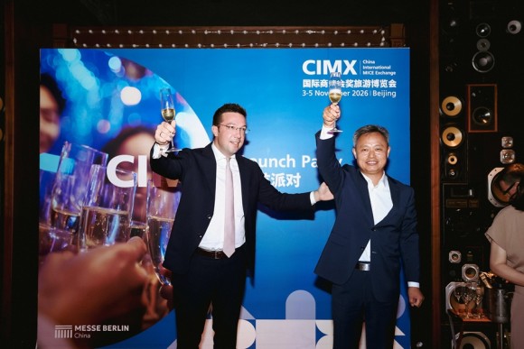 Two Persons standing in front of a backdrop, raising their glasses and smiling